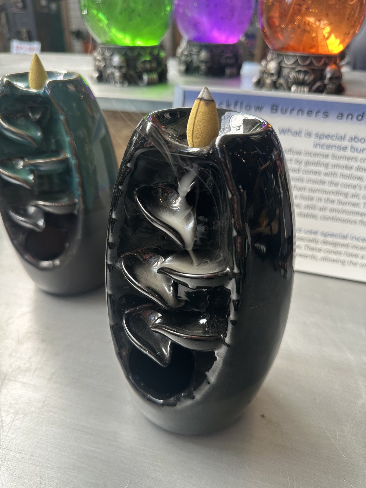 Black Cascade backflow incense burner with a lit cone and smoke flowing down